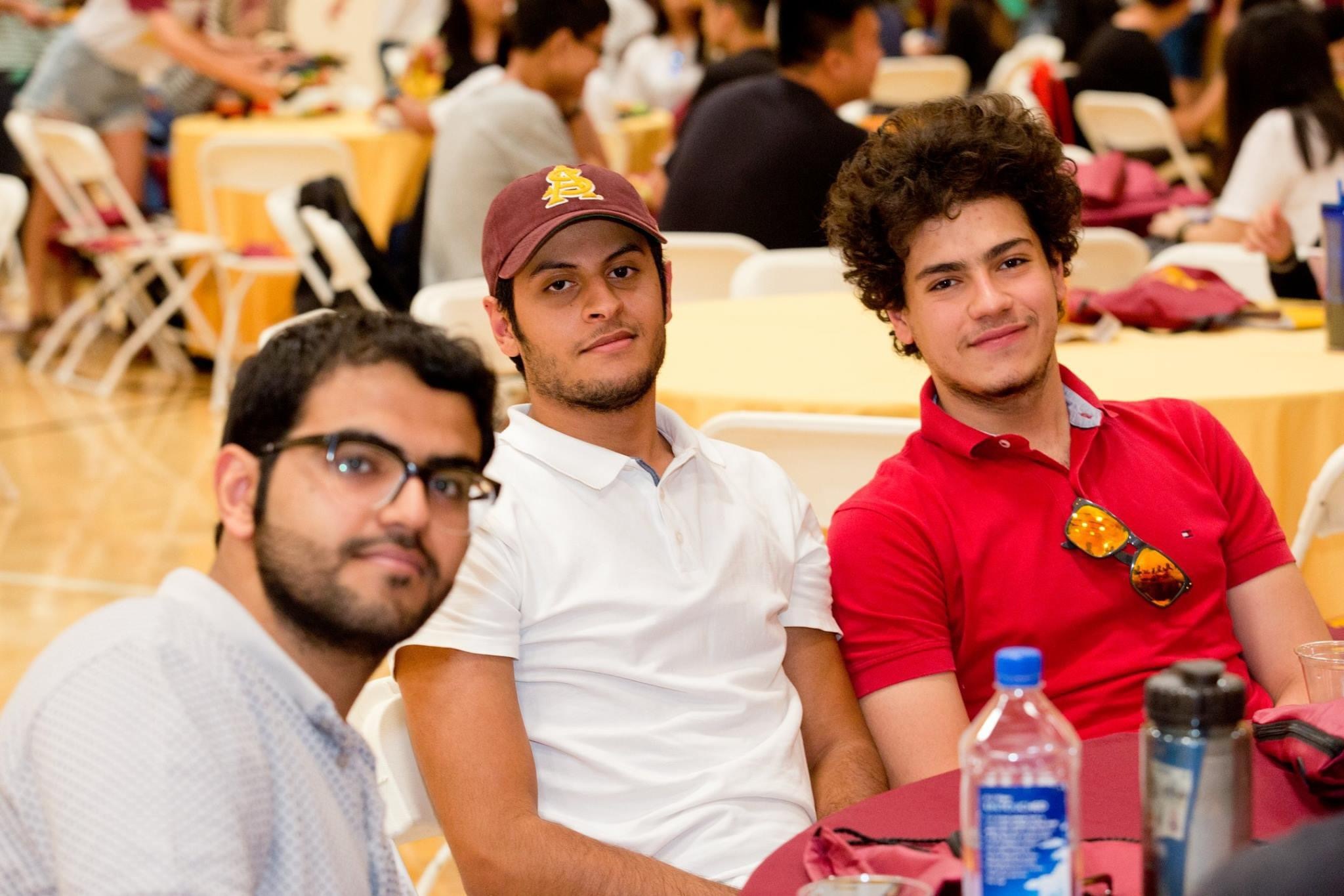 Three international students smile for a photo at student orientation.