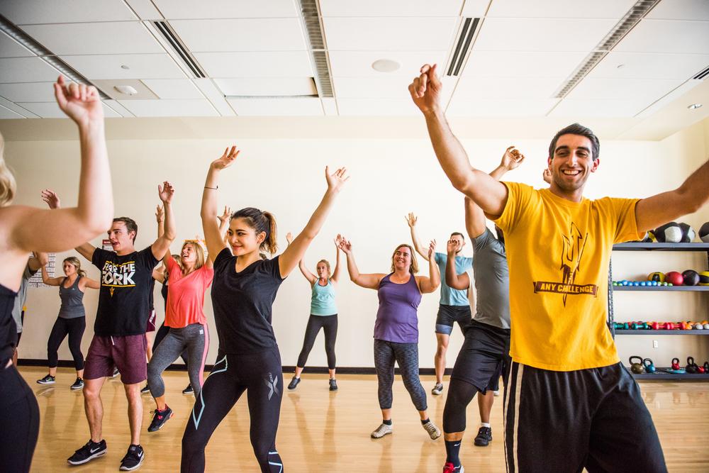 Group of smiling ASU students engaging in aerobic exercise class.