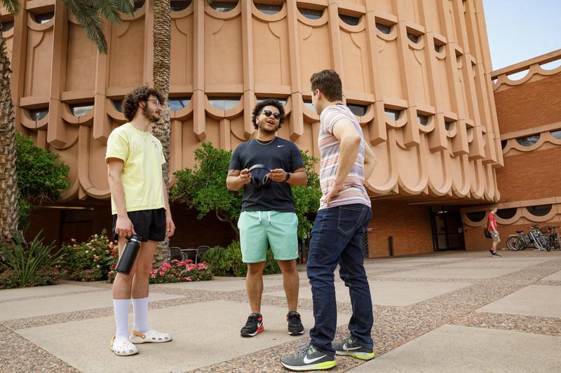Three ASU students having a conversation outside of the Barrett Honors College building on Tempe, AZ campus.
