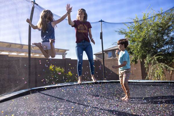 ASU student jumping on a trampoline with two kids giving a high five.