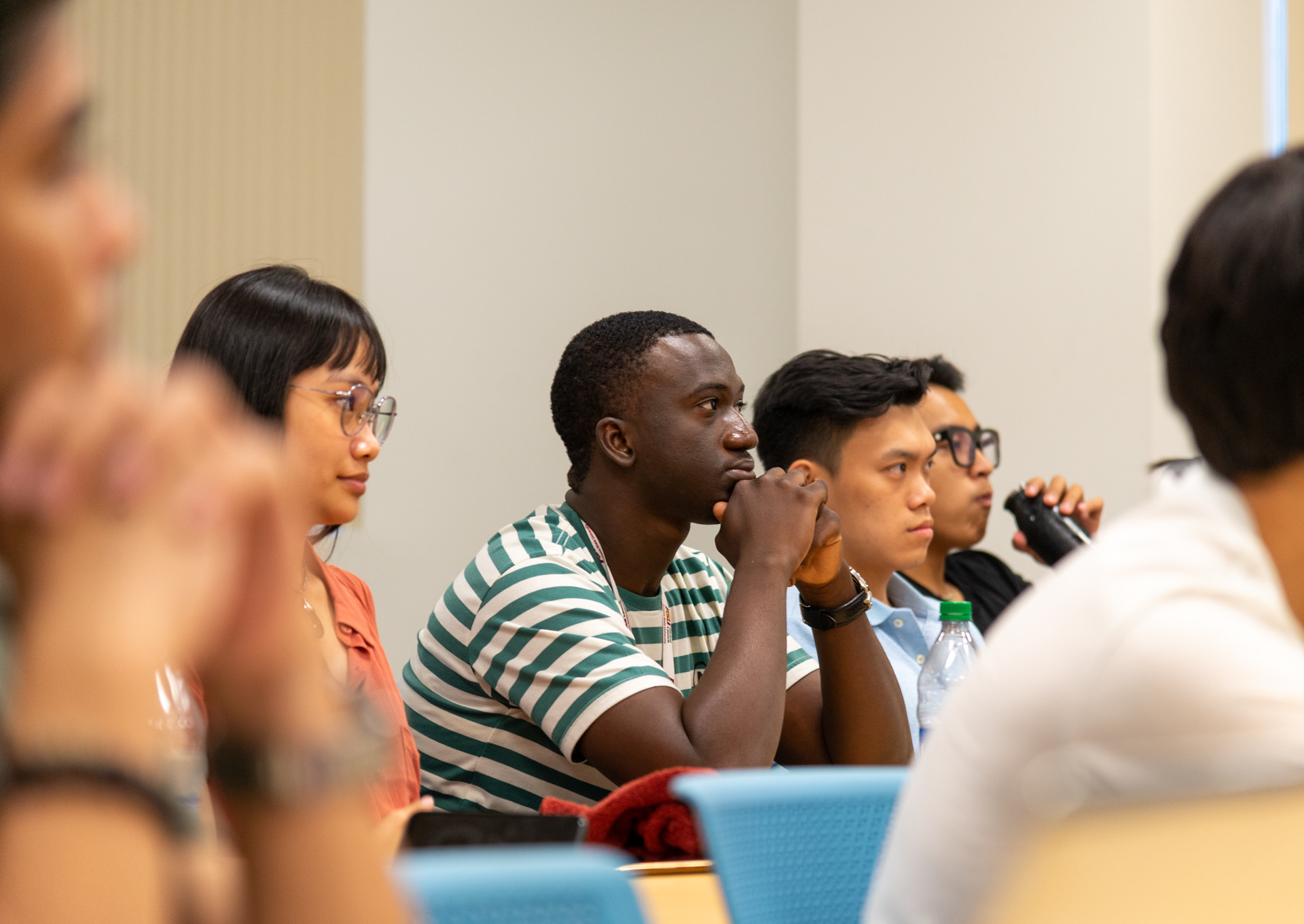 Several students sitting in a classroom listening intently.