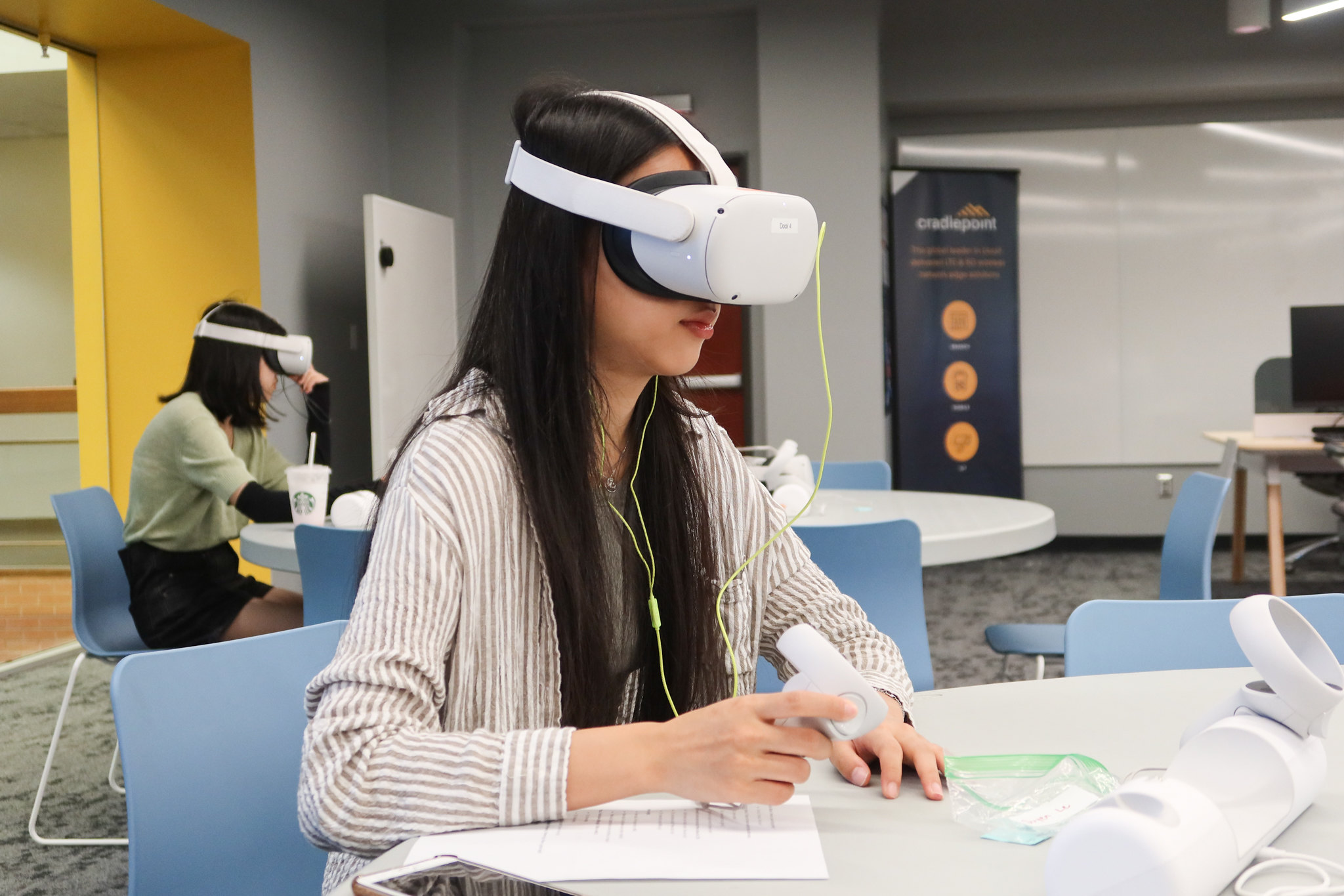 Female student sitting in a class engaged in a VR session.