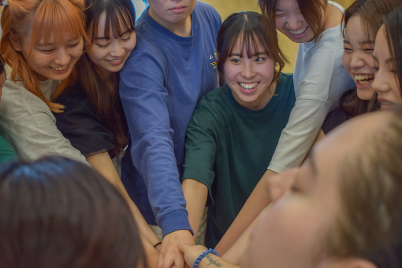 A group of students in a huddle talking about a game they are playing.