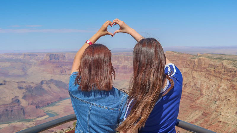 Two ASU students creating a heart shape with their hands at the Grand Canyon.