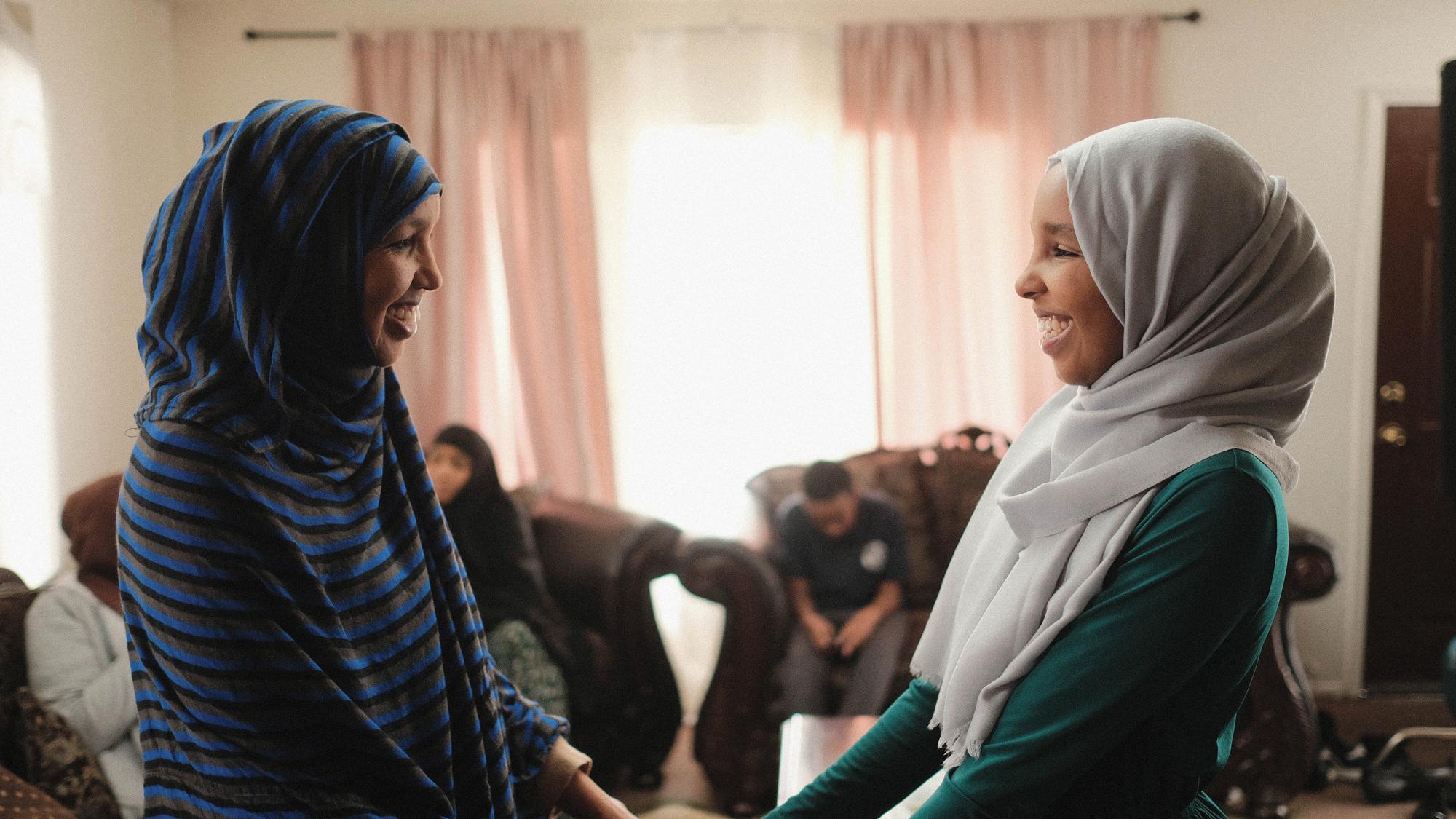 Two female ASU Muslim students smiling at each other in a welcoming manner.