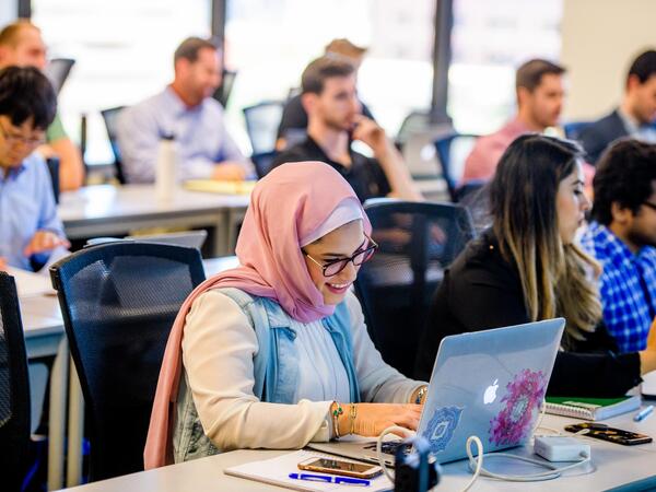 A smiling ASU student at her laptop in class.