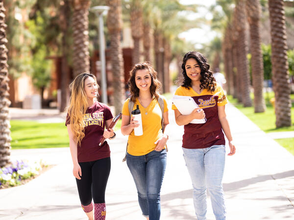 Three happy ASU students walk down Palm Walk on Tempe campus, ready for class