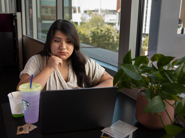 A female student gazing forlornly at her laptop in thought.