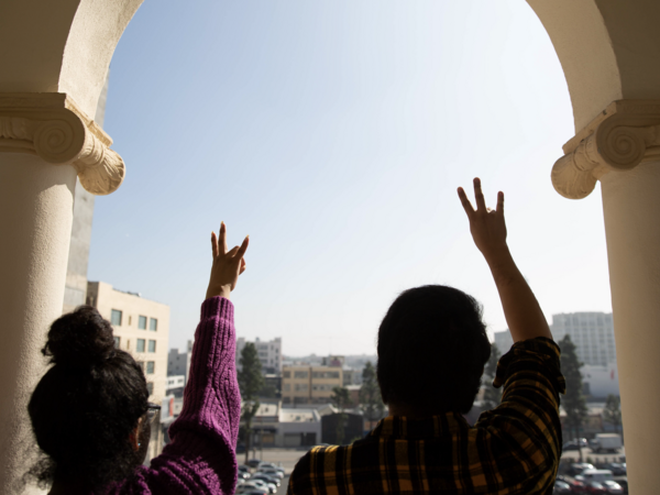 Two ASU students holding up the pitchfork symbol looking out toward campus.