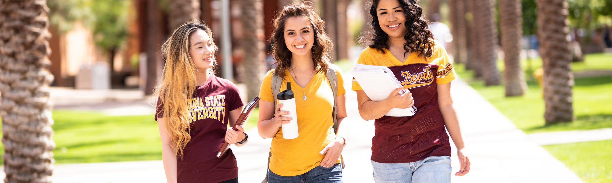 Three happy ASU students walk down Palm Walk on Tempe campus, ready for class