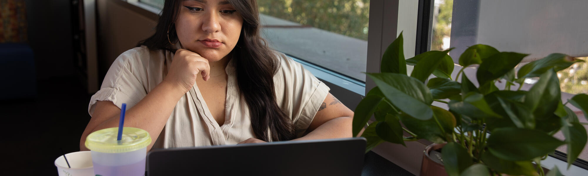 A female student gazing forlornly at her laptop in thought.