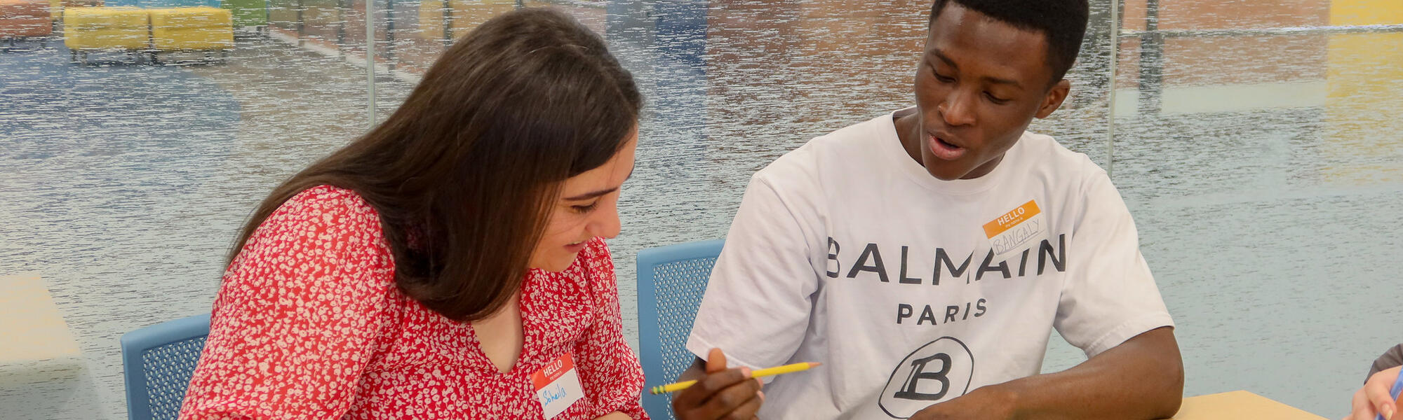 Two students discussing their work writing down answers in a classroom.