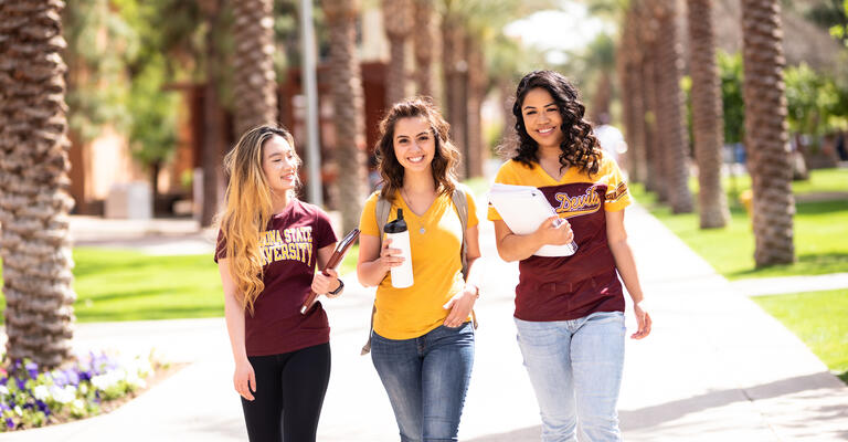 Three happy ASU students walk down Palm Walk on Tempe campus, ready for class