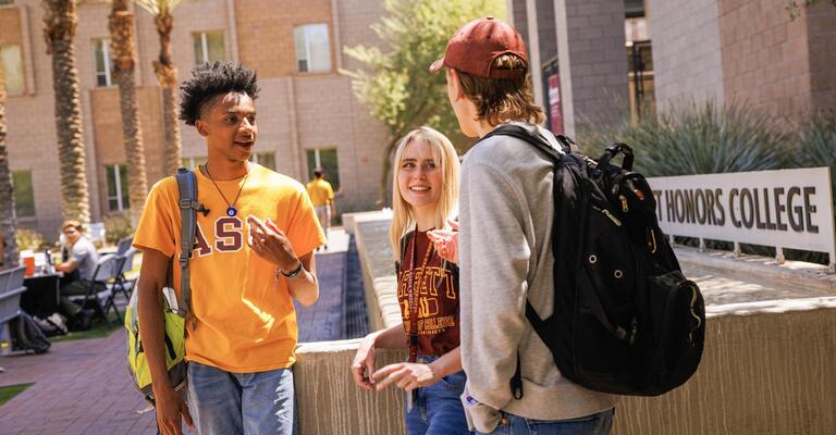 Three ASU students having a conversation outside of the Barrett Honors College building on Tempe, AZ campus.