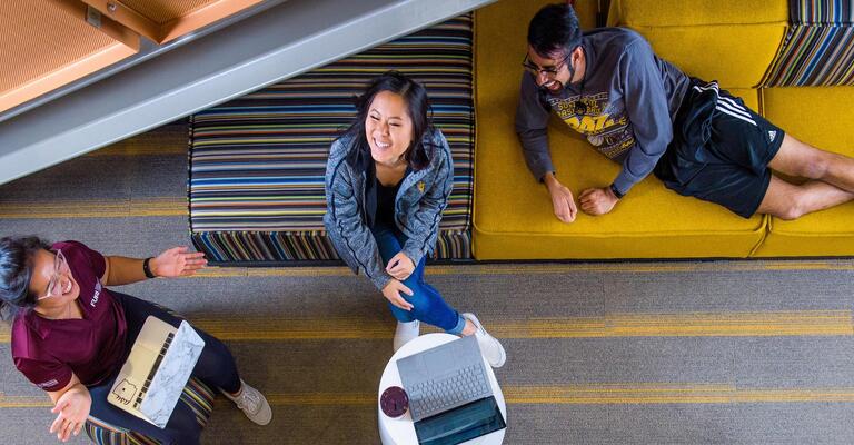 Four ASU students relax in a lounge, happy and talking.