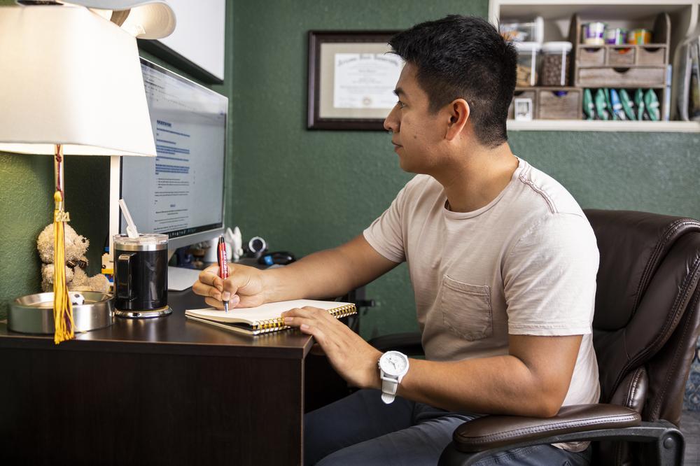 A prospective college student taking notes at his home computer.