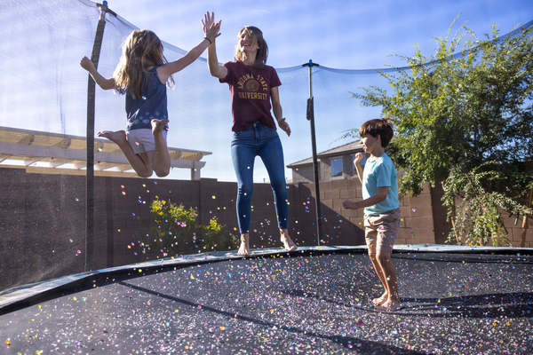 ASU student jumping on a trampoline with two kids giving a high five.