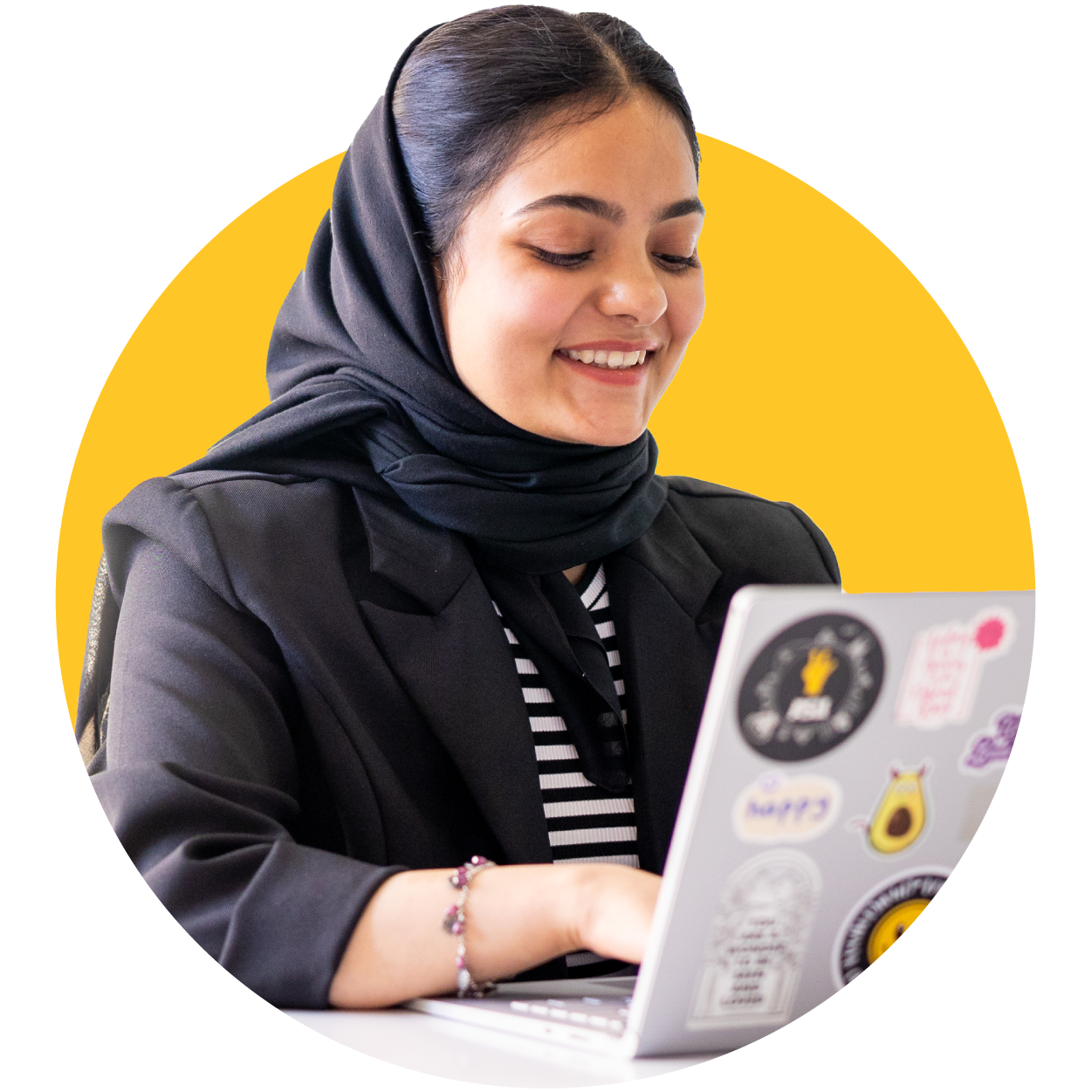 Person smiling while using a laptop with various stickers.