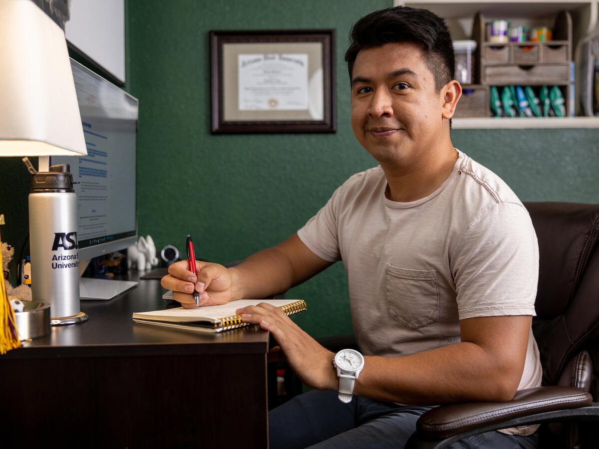 ASU student sitting at his desk writing.