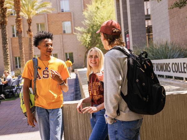 Three ASU students having a conversation outside of the Barrett Honors College building on Tempe, AZ campus.