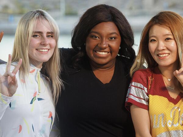 Three smiling ASU students showing the pitchfork sign.