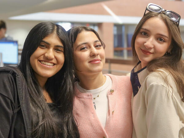 Three female ASU students pose together near the Global Launch Welcome Desk.