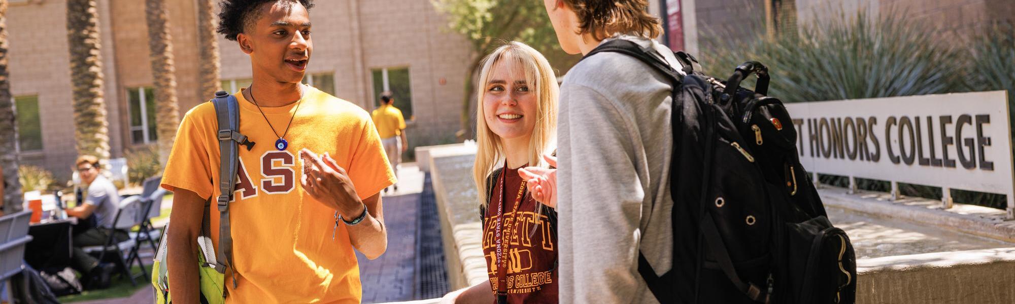 Three ASU students having a conversation outside of the Barrett Honors College building on Tempe, AZ campus.