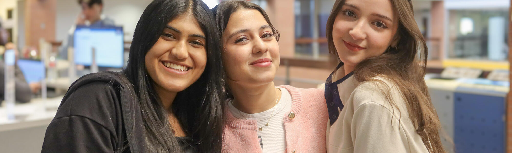 Three female ASU students pose together near the Global Launch Welcome Desk.