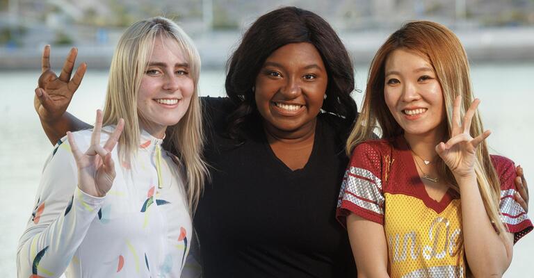 Three smiling ASU students showing the pitchfork sign.